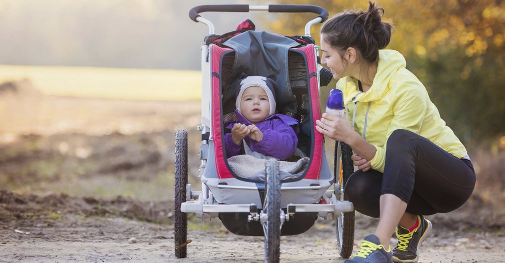 Mutter joggt mit Baby im Kinderwagen