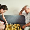 Jugendliche und Großvater spielen Schach auf dem Sofa