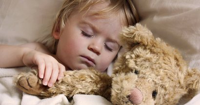 Kleinkind mit Teddy im Arm schläft