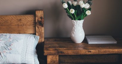 Leeres Bett mit Blumenvase auf dem Nachttisch