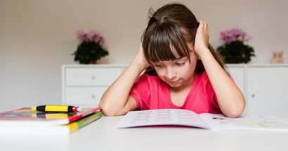Grundschulkind Mädchen sitzt frustriert am Schreibtisch