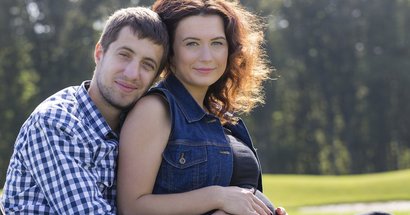 Mann umarmt schwangere Frau und berührt den Babybauch