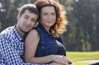 Mann umarmt schwangere Frau und berührt den Babybauch