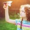 Mädchen lässt Papierflugzeug im Wald steigen