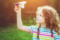 Mädchen lässt Papierflugzeug im Wald steigen