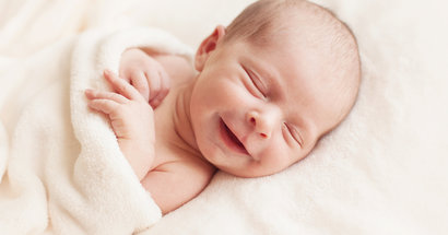 Säugling schläft und lächelt im Schlaf