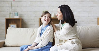 Mutter im Gespräch mit Tochter auf dem Sofa