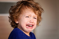 Kleiner Junge mit wuscheligem Haar weint.