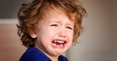 Kleiner Junge mit wuscheligem Haar weint.