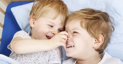 Zwei Geschwister-Kinder mit kleinem Altersunterschied lachen miteinander