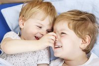Zwei Geschwister-Kinder mit kleinem Altersunterschied lachen miteinander