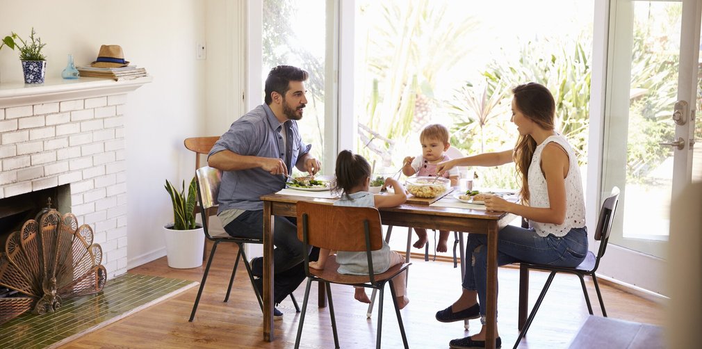 Mutter Vater und zwei Kinder sitzen am Tisch und essen.