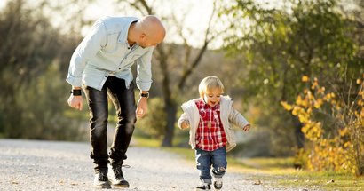 Zweites Lebensjahr: Vater und Kleinkind laufen nebeneinander