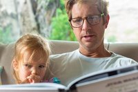 Vater liest Tochter aus einem Buch vor.