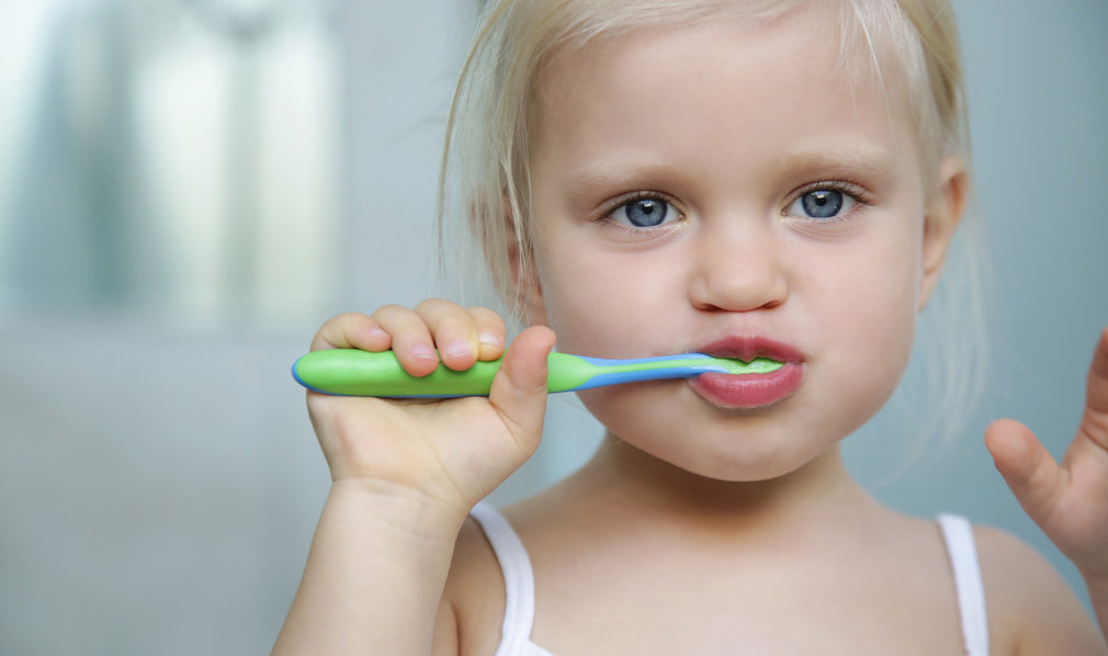 Kleines Mädchen hält Zahnbürste im Mund. Zähneputzen.