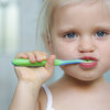 Kleines Mädchen hält Zahnbürste im Mund. Zähneputzen.