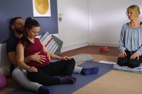 Schwangere und Partner meditieren mit Hebamme.