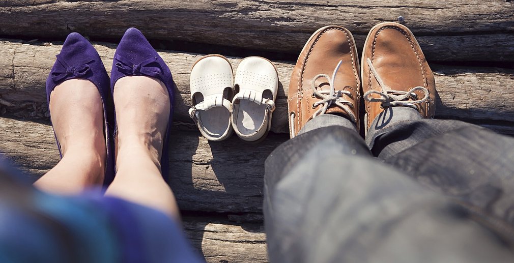 Füße der Eltern neben den Schuhen des Kindes