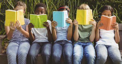 Fünf Kinder mit Büchern vor dem Gesicht