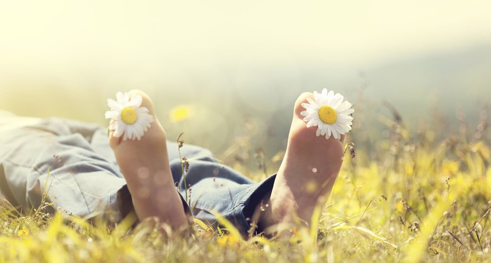 Teenagereltern: Entspannte Füße mit Blumen auf Wiese