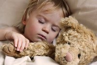 Kleinkind mit Teddy im Arm schläft