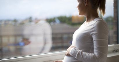 Schwangere blickt aus dem Fenster