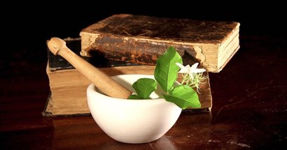 Mörser mit Pflanze und altem Medizienbuch