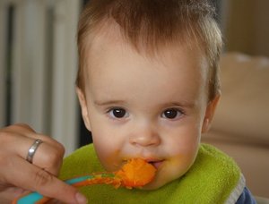 Baby isst Brei mit Löffel