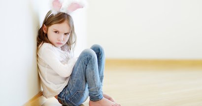 Strafen in der Erziehung: Kind sitzt schmollend auf dem Boden