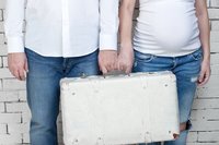 Mann und schwangere Frau mit Koffer