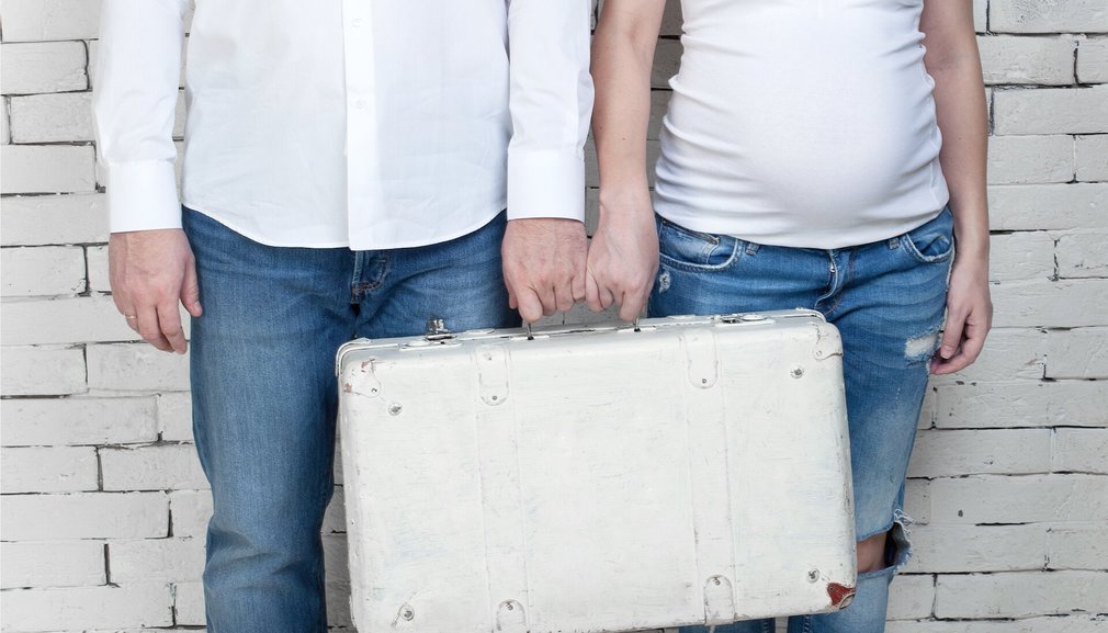 Mann und schwangere Frau mit Koffer