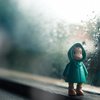 Einsame Puppe vor verregnetem Fenster