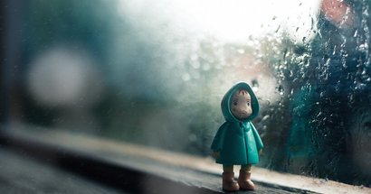 Einsame Puppe vor verregnetem Fenster