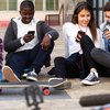 Vier Jugendliche auf dem Bürgersteig an ihren Smartphones