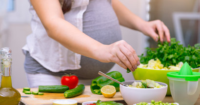 Schwangere Frau bereitet gesundes Essen vor.