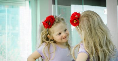 Kita Mädchen mit Blume im Haar steht vor dem Spiegel