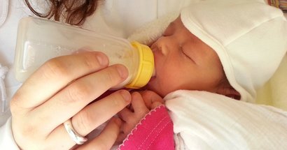 Baby bekommt die Flasche im Arm der Mutter
