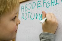 Kind schreibt das Alphabet an Tafel
