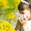 Schulkind mit Allergie putzt sich die Nase vor gelben Blumen