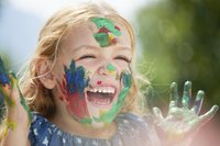 Kreativität: Kind beim Malen mit Farbe im Gesicht