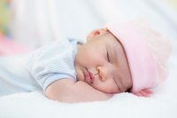 Süsses Baby schläft auf dem Bauch mit rosa Mütze
