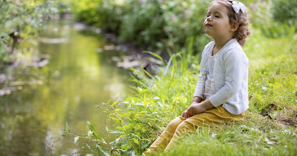Mädchen sitzt am Fluss und genießt die Natur