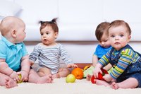 Vier Kleinkinder im Halbkreis spielen