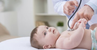 Baby liegt auf Rücken beim Arzt und wird untersucht