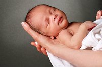 Neugeborenes schläft auf Händen der Mutter.