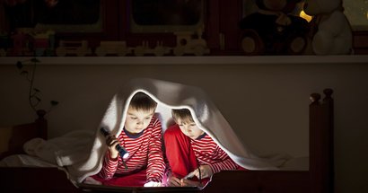 Übernachtungsbesuch: Zwei Freunde lesen nachts unter der Decke