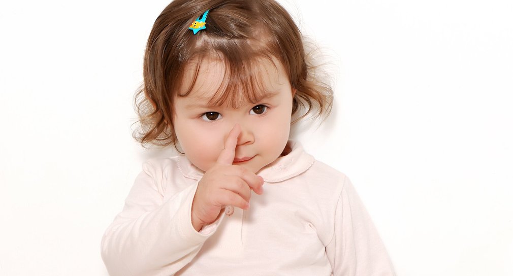 Kleines Mädchen hält Finger an Nase. Gebärde.